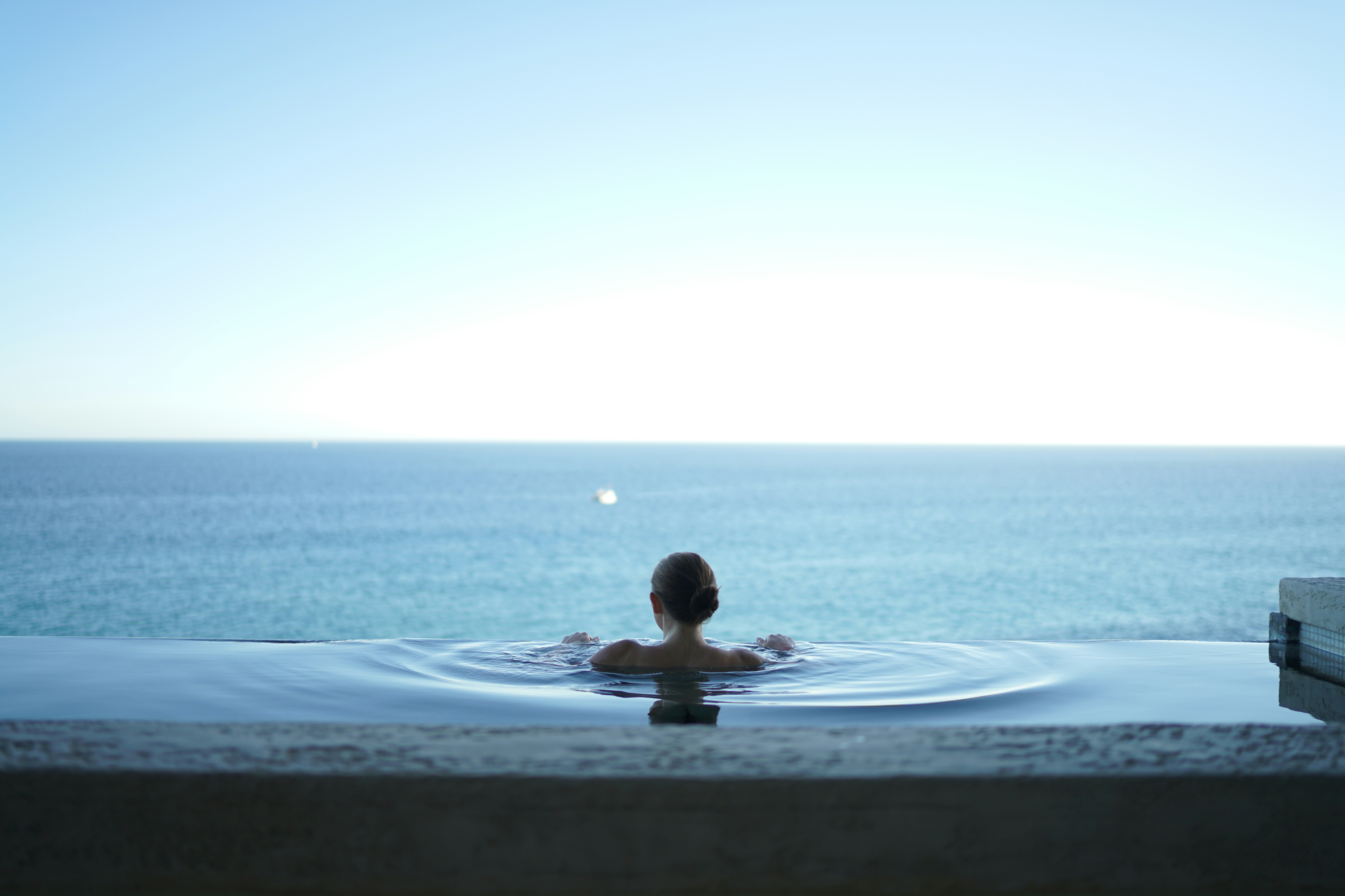 Woman relaxing poolside at golden hour, bespoke luxury travel atmosphere