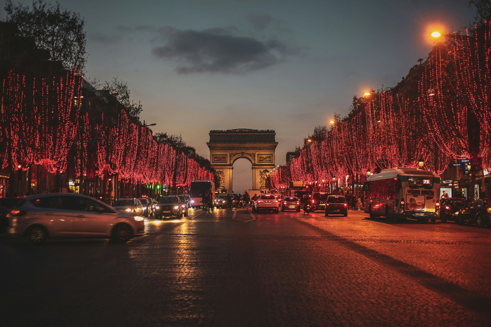 Paris at night — famous Champs-Élysées leading to historic Arc de Triomphe, illuminated with elegant city lights